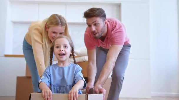 Радостные мать и отец переместить картонную коробку с дочерью — стоковое видео