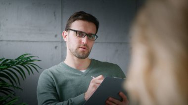 Genç, profesyonel bir psikoterapist hastaya depresyonun nedenlerini anlatıyor.