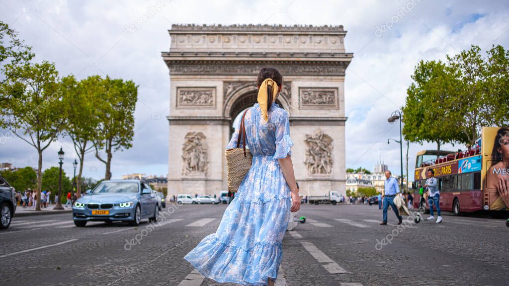 Attractive girl in a blue dress against the backdrop of the Arc de Triomphe in Paris