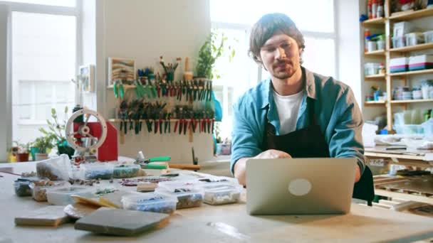 Feliz hombre lleva a cabo la formación en línea utilizando un ordenador portátil en el estudio — Vídeo de stock