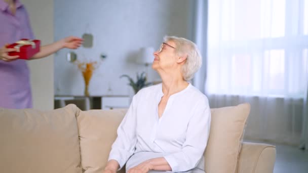 Sorrindo filha dando um presente para uma mãe idosa feliz — Vídeo de Stock