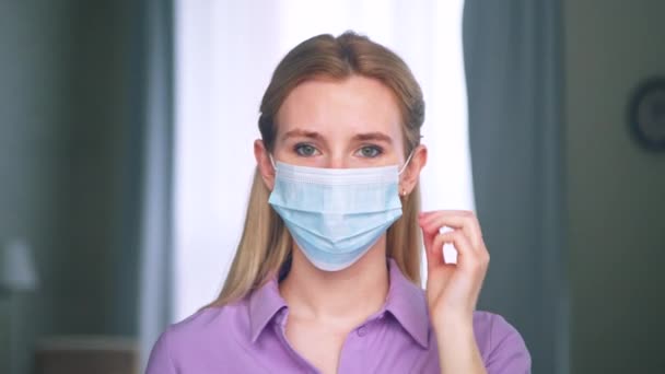 의료용 푸른 마스크를 벗고 있는 젊은 여자 — 비디오