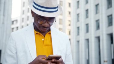 Gözlüklü ve şapkalı Afro-Amerikan adam akıllı telefondan konuşuyor.