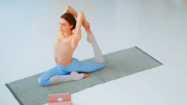 Young woman is engaged in training online. Athletic girl doing yoga — Stock Photo, Image