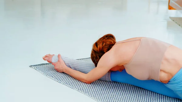 Привлекательный тренер по йоге занимается гимнастикой на коврике для йоги — стоковое фото