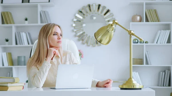 Thinking girl with laptop at the desk at home office — Stock Photo, Image