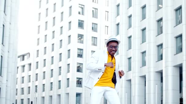 Homem alegre em chapéu de terno e óculos salta e dança sorrindo — Vídeo de Stock