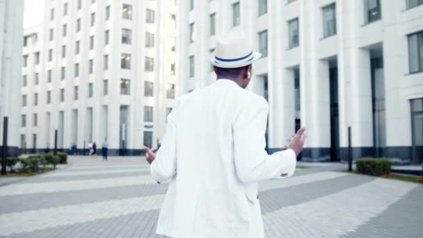 Un afro-american în costum cu pălărie merge de-a lungul trotuarului — Videoclip de stoc