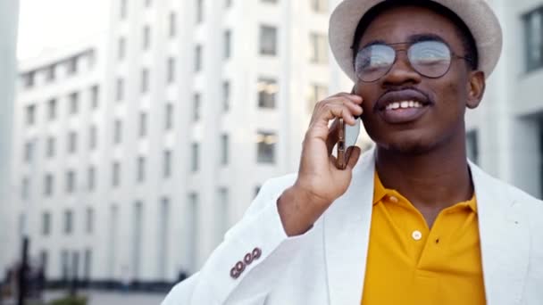 Negru om de afaceri în ochelari și pălărie vorbește pe smartphone — Videoclip de stoc