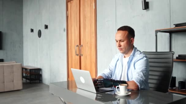 Disabled man with prothesis types on laptop and raises hands — Stock Video