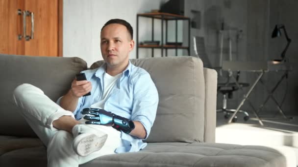 Людина з інвалідністю з біологічною рукою перемикає телевізор — стокове відео