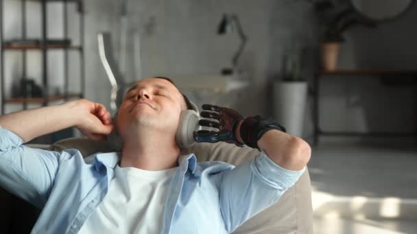 Ontspannen man met zwarte bio hand prothese luistert naar muziek — Stockvideo