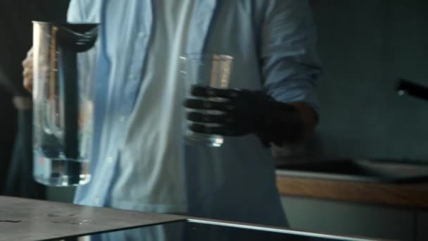 Gehandicapte man met bio hand prothese giet water in glas — Stockvideo