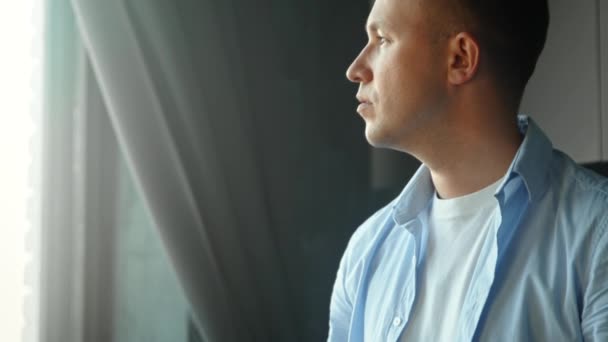 Homme réfléchi avec prothèse de membre bio regarde à l'extérieur de la fenêtre — Video