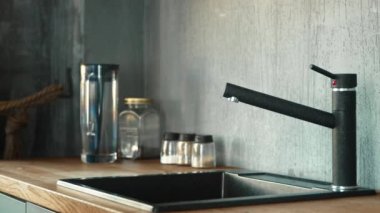 Biyolojik eli olan adam musluğu açar ve su döker.