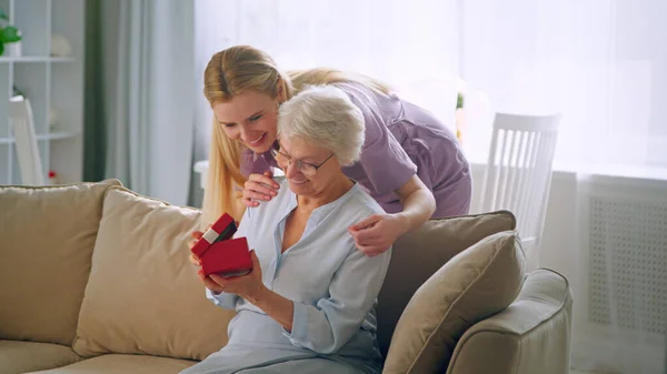 Lächelnde Tochter schenkt einer älteren Mutter zu Hause ein Geschenk — Stockfoto