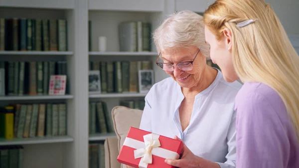 Eine ältere Frau wundert sich über das Geschenk ihrer Tochter — Stockfoto