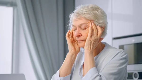 Velho cansado do trabalho senhora aposentada com cabelo cinza curto massagens templos com as mãos — Fotografia de Stock