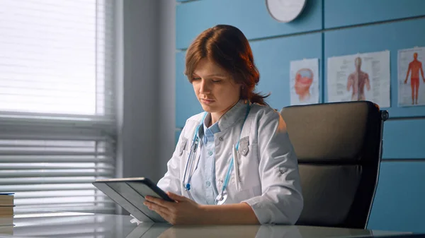 Lady general practitioner in white coat shows patient black tablet display explaining diagnostic at meeting — Stock Photo, Image