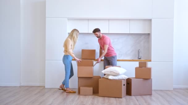 Молодая женщина блондинка и бородатый парень открывают картонную коробку — стоковое видео