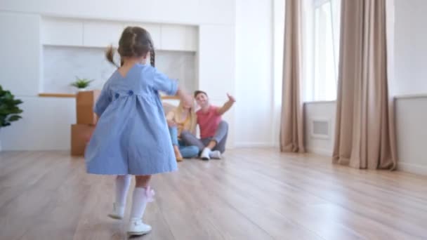 Glückliches Vorschulmädchen mit Zöpfen rennt zu Eltern und umarmt sie — Stockvideo