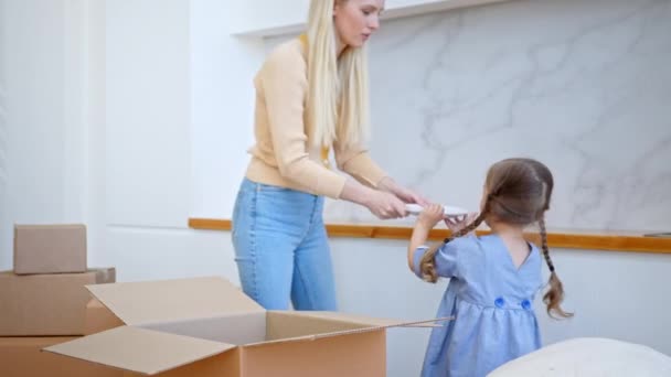 Muchacha divertida con trenzas largas desempaqueta la caja marrón en plano — Vídeos de Stock