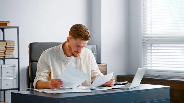 Konzernmanager betrachtet Blätter mit Berichten und analysiert Unternehmenseinkommen — Stockfoto