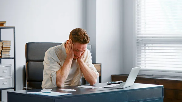 Young male financial director reads bank reports sitting at grey table — Stock Photo, Image