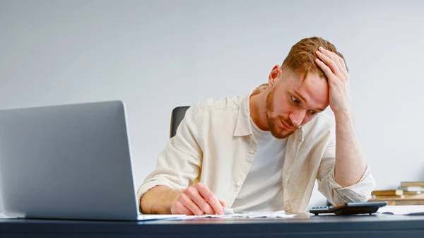 Geconcentreerde en bezorgde manager kijkt naar papieren controles en het totale bedrag op rekenmachine — Stockfoto