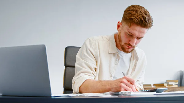 Buchhalter eines Startup-Unternehmens im gelben Hemd fasst unerwartete Ausgaben auf Taschenrechner zusammen — Stockfoto