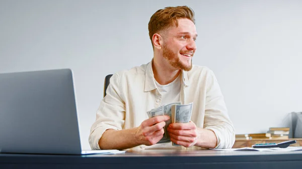 Glimlachende zakenman telt cash inkomsten met dollarbankbiljetten — Stockfoto