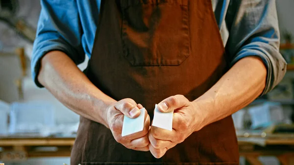 Young man in apron holding a piece of stone close-up — Stock Photo, Image