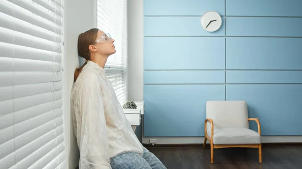 Tired young woman physician therapist in white sterile coat blue mask and glasses — Stock Photo, Image