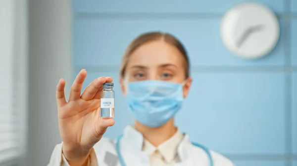 Serious lady doctor holds vaccine against covid in transparent vial standing in hospital laboratory — Stock Photo, Image