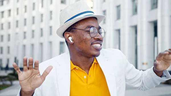 Joyful black man in wireless headphones listens to music and performs contemporary street dance — Stock Photo, Image