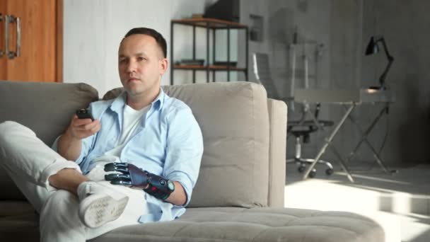 Uomo rilassato con protesi bio mano prende telecomando — Video Stock