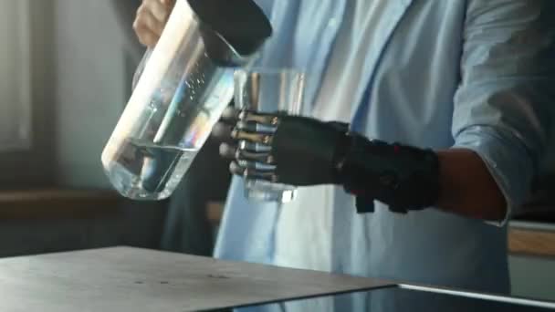 Guy με τεχνητό άκρο ρίχνει νερό σε γυαλί από το μπολ — Αρχείο Βίντεο