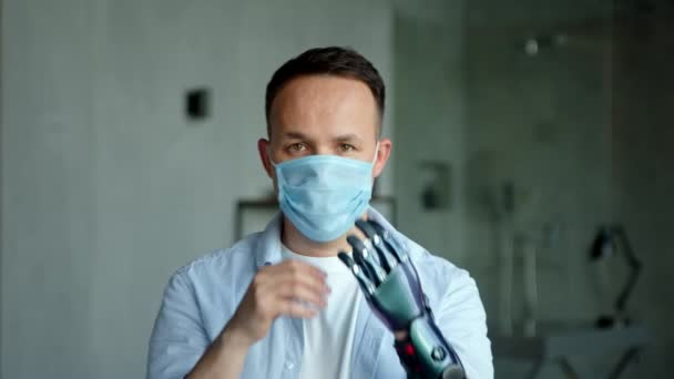 Serieuze man met kunstmatige handprothese neemt af masker — Stockvideo