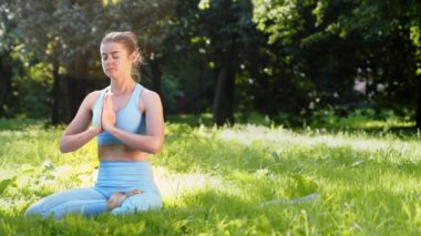 Genç kadın yoga pozisyonunda meditasyon yapıyor ve derin derin nefes alıyor.