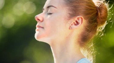 Bayan sporcu rahatlar ve parkta yoga pozu verir.
