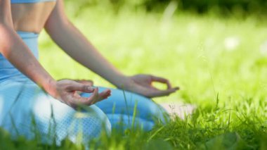 Eşofmanlı genç bayan sporcu yoga pozunda oturuyor.
