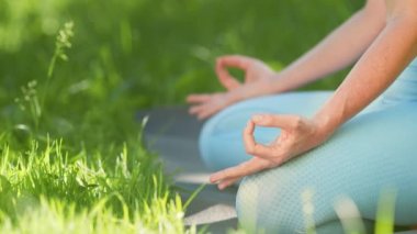 Eşofmanlı genç bayan antrenör yoga pozisyonunda meditasyon yapıyor.