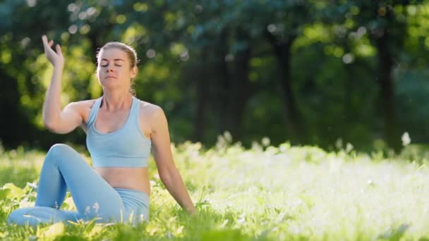 Молодая женщина меняет позы для йоги на луговой траве — стоковое видео