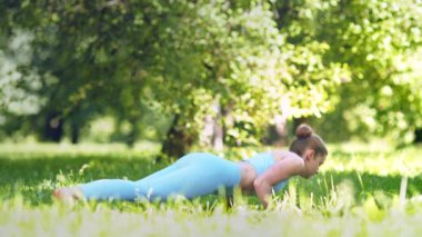 Bayan sporcu yoga yapıyor ve çayırlarda esniyor.