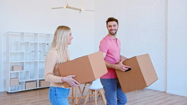 Csodálatos pár férfi és hölgy sétál az új apartman szobában kezében nagy kartondobozok — Stock Fotó