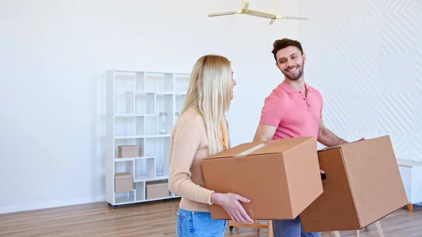 Paar man en blonde dame houdt kartonnen dozen en zet op grote stapel in nieuw appartement — Stockfoto