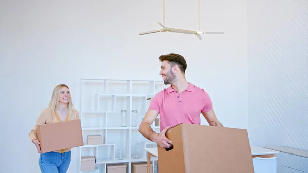 Excited blonde young woman and bearded guy stack cardboard boxes on large pile in new apartment — Stock Photo, Image