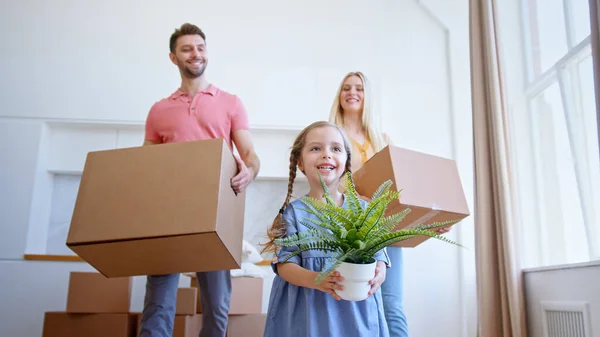 Delighted family parents and preschooler daughter move to new apartment holding brown cardboard boxes — Stock Photo, Image