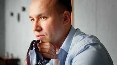 Yüksek tapınağı ve siyah yapay protezi olan düşünceli serbest çalışan bir adam el ele tutuşmayı düşünüyor.