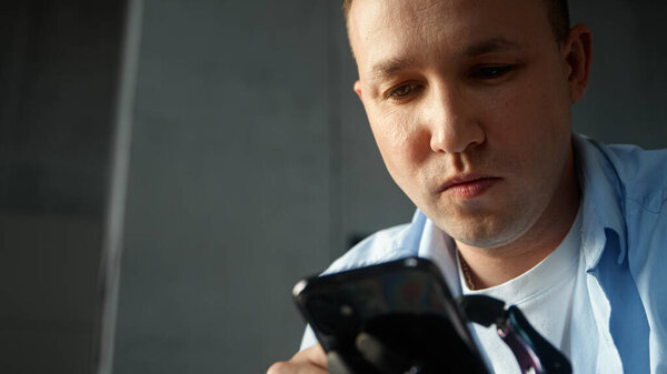 Сконцентрированный мужчина в синей рубашке типа на смартфоне держит устройство в черной искусственной конечности протез руки